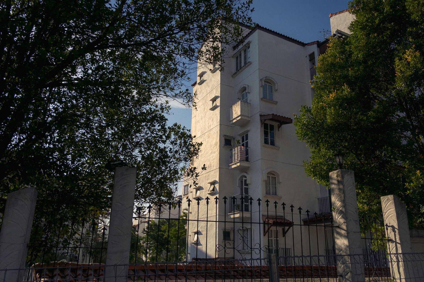 A Kuala Lumpur residential building seen through sunlit tropical trees